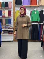 Kahverengi burgu kumaş uzun bayan gömlek ve siyah pantolon giyen şık kadın modeli, konforlu tarzını sergiliyor.